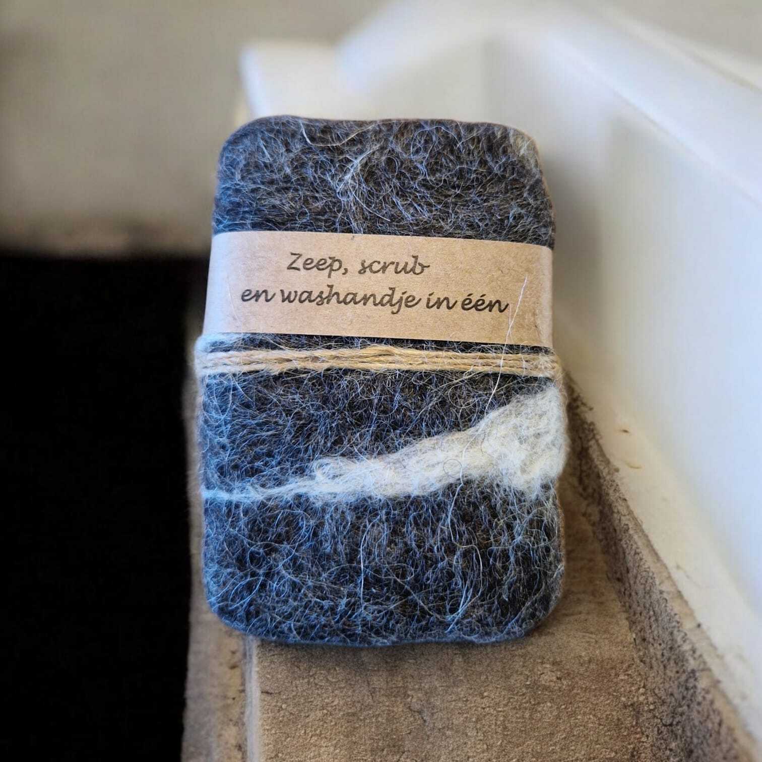 Gevilt zeepje van grijze wol met label zeep, scrub en washandje in een